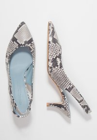 Scarpe con tacco alto a punta con una stampa a serpente bianca e nera, dotate di un'apertura curvata sul lato e di una soletta blu chiaro.