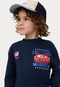 Marinblå långärmad skjorta med en grafik av Lightning McQueen, med röda och blå accenter, samt en basebollkeps med mesh-bak.