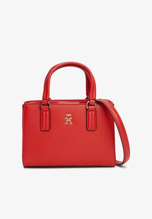Rode leren handtas met dubbele handvatten, verstelbare schouderband en klein goudkleurig logo-embleem aan de voorkant.