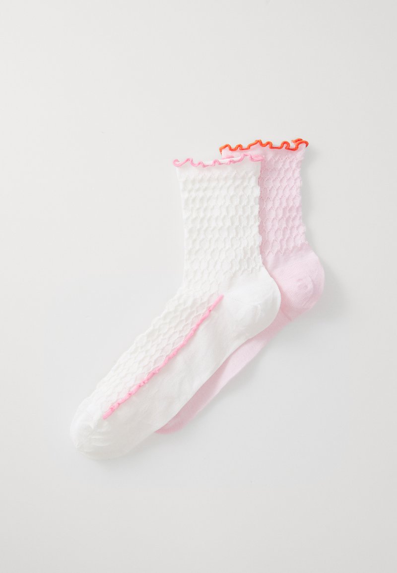 White and pink ankle socks with a textured, honeycomb design and ruffled hems. The white sock has pink trim, while the pink sock features orange trim.