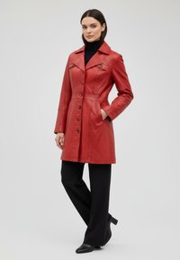 Red leather coat with a tailored fit, notched collar, six buttons, and visible stitching. Worn over black wide-leg pants and heeled boots.