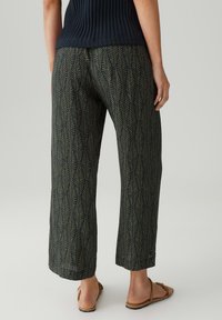 Pantaloni cropped con una base verde scuro, caratterizzati da un motivo a foglia ripetuto in verde chiaro. Realizzati in tessuto morbido e leggero.