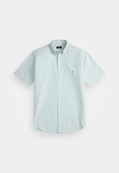 Camisa de botão de manga curta azul claro, feita de algodão, com colarinho clássico, um pequeno logo bordado no peito e uma bainha arredondada.