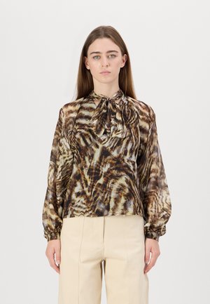 Blouse à motifs marron et crème en tissu léger, avec un nœud au cou et de longues manches flottantes à poignets élastiques.