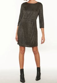 Svart glittrande klänning med trekvartslånga ärmar, rund halsringning och volangdetalj i midjan; matchad med ankelstövlar.