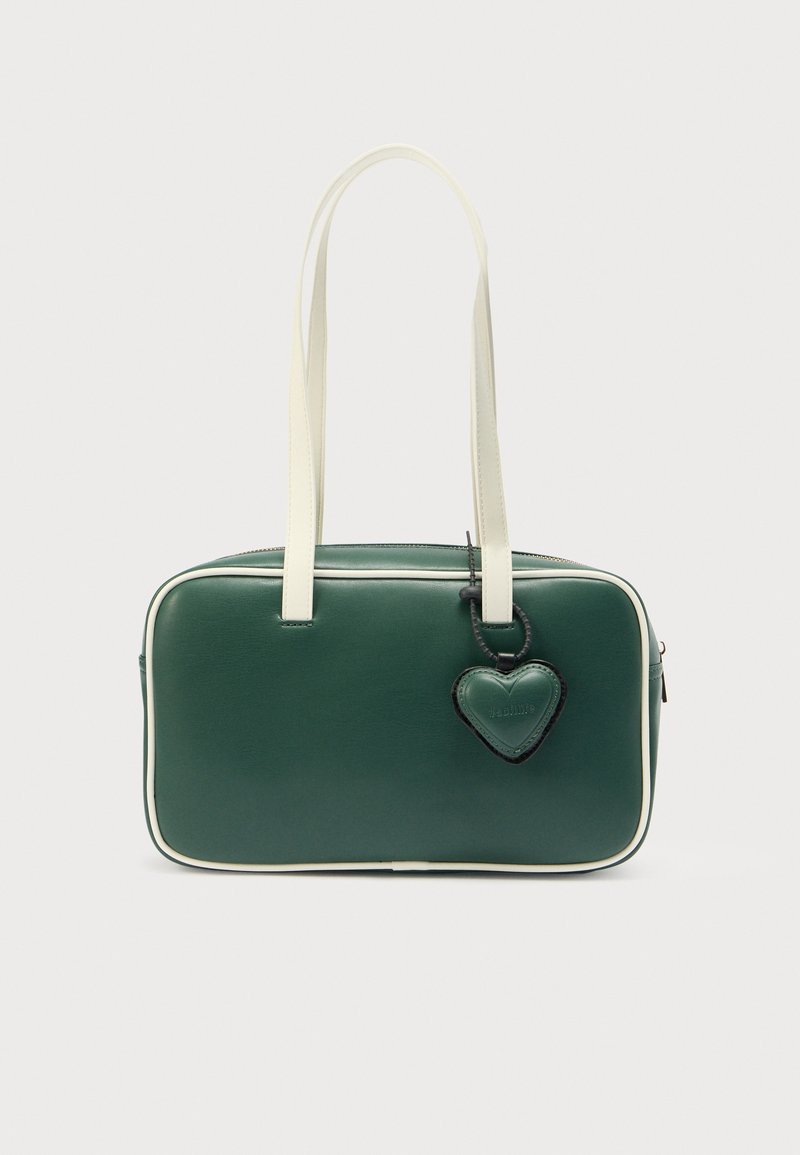 Grøn lædertaske med hvide detaljer, rektangulær form, to top-håndtag og en hjerteformet charm vedhæftet en lynlås.