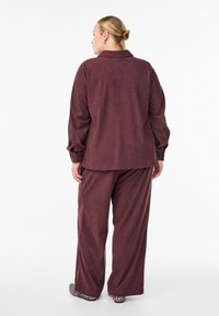 Rust-colored corduroy shirt and matching pants, featuring a relaxed fit and button details. Soft texture with wide-leg design.
