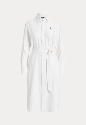 Robe-chemise blanche à manches longues, boutonnée sur le devant, avec un col pointu, un lien à nouer à la taille et un petit logo brodé sur la poitrine.