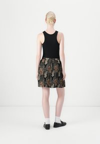 Top negro sin mangas combinado con una falda acampanada de diseño de estampado animal colorido en tonos marrón y beige, de longitud justo por encima del muslo.