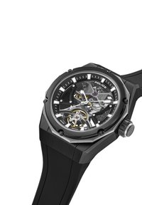 Črna skeletna ura z okroglim številčnico, ki ima prozoren cifer, zlato akcentiranje in srebrne označevalce ur na gumijastem pasu. Oblika ohišja je šestkotna.