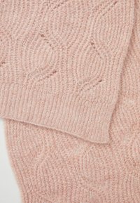 Różowy sweter z dzianiny z teksturowanym wzorem przypominającym liście. Miękka, puszysta faktura oraz widoczne prążkowane krawędzie.