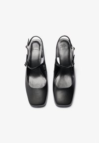 Sorte læderslingback-sko med firkantet tå, glat tekstur og en enkelt rem over anklen, med en lav, blokhæl.