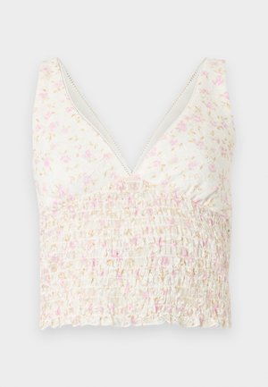 Bela pristrižena majica z rožnim potiskom v roza in bež barvah, z globokim V-izrezom in nabranim pasom.