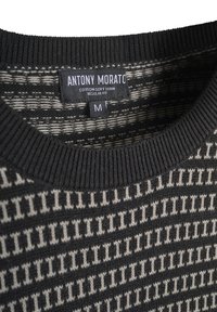 Crna i bijela pletena majica sa geometrijskim uzorkom, rebrastim izrezom i etiketom od tkanine koja glasi "Antony Morato", veličina M.