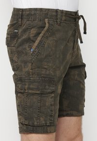Cargo-Shorts aus olivgrünem Stoff mit strukturiertem Muster, ausgestattet mit einem elastischen Bund, frontalen Taschen und einer seitlichen aufgesetzten Tasche.