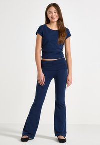 Marineblaues, tailliertes T-Shirt mit kurzen Ärmeln und passenden, ausgestellten Hosen, aus glattem, elastischem Material gefertigt. Einfaches Design, ohne sichtbare Muster.