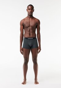 Zwarte katoenen boxershorts met een elastische tailleband met het "LACOSTE"-logo. Glad textuur, aansluitend ontwerp, middellange pijpen zonder patronen.