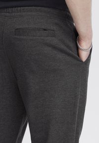 Grijze sweats met een zachte stof hebben een zijzak en een elastische tailleband. De textuur lijkt glad met een casual pasvorm.