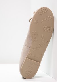 Suedes ballerina i lys beige med rund tå, snore detaljer og en fleksibel gummisål med trykte ballerina designs.