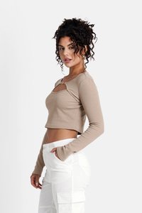 Beige gestreifter langärmeliger Crop-Top mit quadratischer Aussparung und goldenen Hardware-Details, kombiniert mit weißen Cargo-Hosen. Glatte Textur.