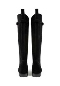 Bottes noires en daim haute jusqu'au genou avec une texture lisse, de subtils détails de couture et des sangles ajustables à l'arrière. Semelles en caoutchouc plates.