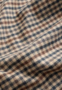 Õmmeldud kangas, millel on ruuduline muster pruunide, siniste ja beežide toonidega. Pehme tekstuur, diagonaalses voldis laotud.