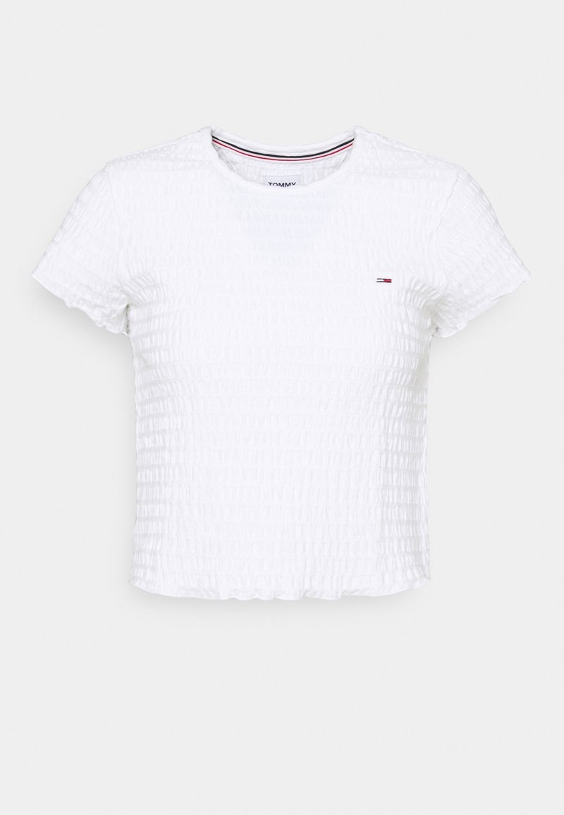 Chemise blanche à manches courtes avec un tissu texturé et un design froncé. Elle présente un col rond et un petit logo sur la poitrine gauche.