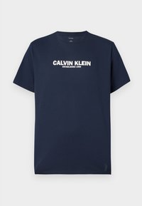 Tumši zilas krāsas kokvilnas t-krekls ar īsām piedurknēm un apaļu kakla izgriezumu. Centrā rakstīts balts teksts "CALVIN KLEIN ESTABLISHED 1968."