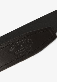 Czarny skórzany pasek z wytłoczonym logo; charakteryzuje się gładką fakturą i kontrastowym materiałowym tłem, z wyraźnym przeszyciem.