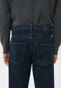 Los vaqueros de mezclilla azul oscuro tienen un corte recto con dos bolsillos traseros, un acabado ligeramente texturizado y un diseño clásico de cinturilla.