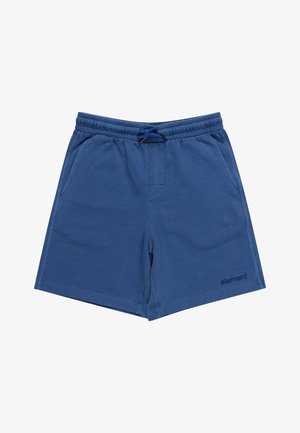 Teenager iført en hvid Element-logo t-shirt, blå Element-shorts, brune sneakers og armbånd på hver håndled, stående mod en hvid baggrund.
