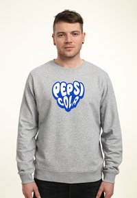 Felpa grigia realizzata in un misto di cotone, con il logo blu "PEPSI COLA" sul davanti. Collo rotondo e maniche lunghe con polsini a coste.