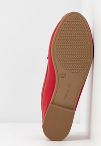Chaussure plate rouge affichant une semelle texturée couleur beige taille 37 avec la marque "Tamaris" sur fond blanc uni.