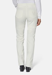 Weiße gerade Bein-Hosen mit zwei Gesäßtaschen; eine Tasche hat ein gesticktes "M". Hergestellt aus einem glatten Baumwollmischgewebe.