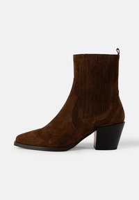Botine din suede maro, cu vârful ascuțit, detalii cusute și toc pătrat. Dispune de o bandă de tragere pentru a fi ușor de încălțat.