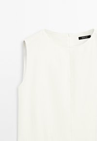White sleeveless top with a round neckline and a discreet back zipper. Smooth texture, minimalist design, and no visible patterns or accents.