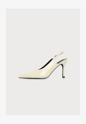 Kremowy, szpiczasty but na wysokim obcasie typu slingback z cienką szpilką i czarną podeszwą, widziany z boku.