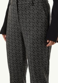 Black pants featuring a repeating geometric pattern in light gray. Made from fabric with a smooth texture. Includes side pockets.