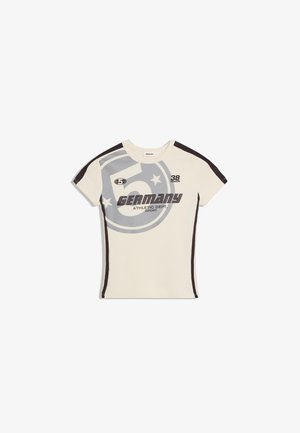Krem športna majica kratkih rokavov s črnimi stranskimi črtami in napisom "Germany Athletic Dept. Sport" z zvezdami in številko 5 na sprednji strani.