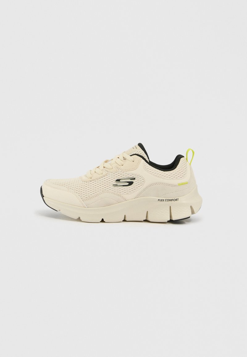 Zapatillas deportivas de color beige claro con parte superior de malla, acentos negros, diseño con cordones y suela gruesa marcada "FLEX COMFORT". Tira trasera en amarillo neón.