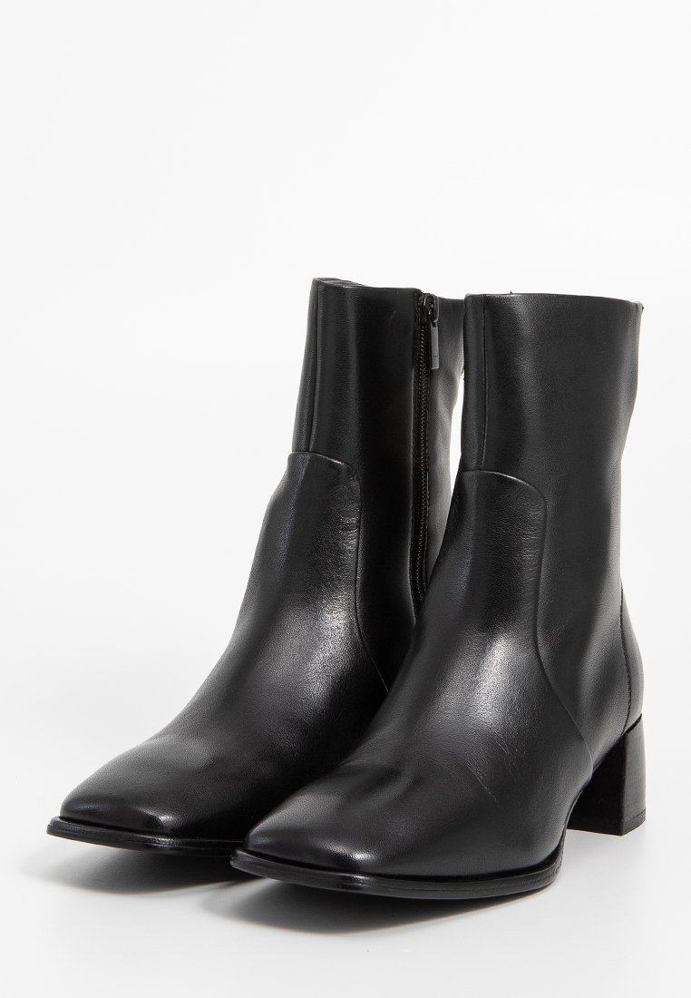 Stivali ankle in pelle nera con punta affusolata, chiusura con zip sul retro e tacco a blocco di 5 cm. Texture liscia con accenti di design minimi.