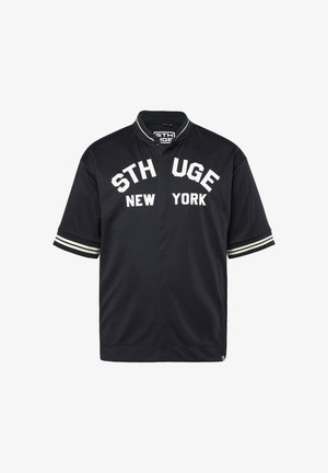 Schwarzes Sportshirt mit kurzen Ärmeln, weißen gestreiften Bündchen und weißem Schriftzug "STH UGE NEW YORK" auf der Brust.
