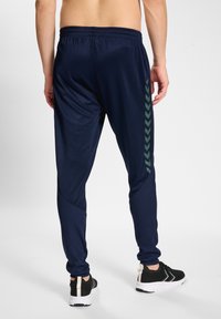 Pantaloni sportivi blu marina con una superficie liscia, caratterizzati da motivi a zigzag verdi sui lati e una vita elasticizzata per il massimo comfort.