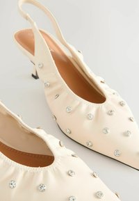 Kermaviininväriset nahka-slingback-korkokengät, joissa on terävä kärki, rypytetty muotoilu, koristeltuna strasseilla ja metallinpintaisilla napeilla, ohuella mustalla korolla.