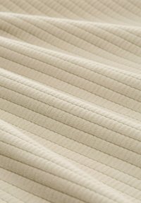 Texturiertes Gewebe in hellem Beige mit subtilen vertikalen Streifen. Weiche, glatte Textur mit leicht geripptem Finish und einem einheitlichen Muster.