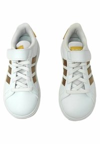 Baskets de sport blanches avec trois rayures brunes, bout rond, devant à lacets et sangle Velcro, présentant une doublure en mesh et un col rembourré.