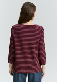 Haut bordeaux à manches longues avec des rayures horizontales, col arrondi et tissu en mélange de coton doux. Il présente une coupe décontractée et des manches mi-longues.