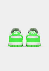 A Nike Dunk Low sportcipő fehér felsőrésszel rendelkezik, neon zöld kiegészítőkkel, texturált részletekkel, párnázott szegéllyel és gumitalppal.