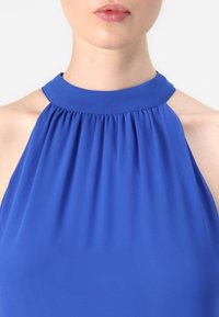 Kungablå halterneck-top med plisserad detalj vid halsringningen, tillverkad av ett slätt tyg, med en figurnära bodice och ärmlös design.