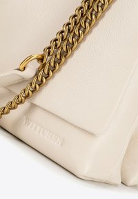 Sac à main en cuir beige avec une surface texturée, doté d'une bandoulière en chaîne dorée et d'un logo "WITCHE" embossé au fond.